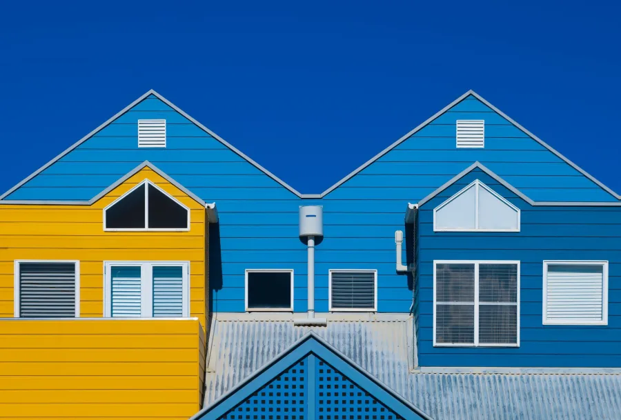 The Woodlands - Bright blue and yellow facades of modern houses with symmetrical designs under a clear sky
